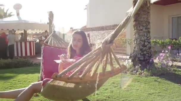 Девушка сидит в гамаке — стоковое видео