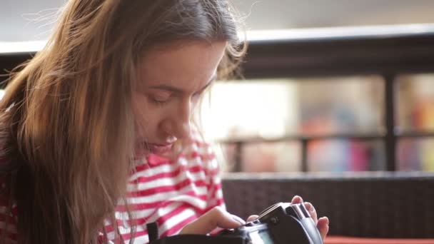 Ragazza seduta sul divano e guardando le immagini dalla fotocamera — Video Stock