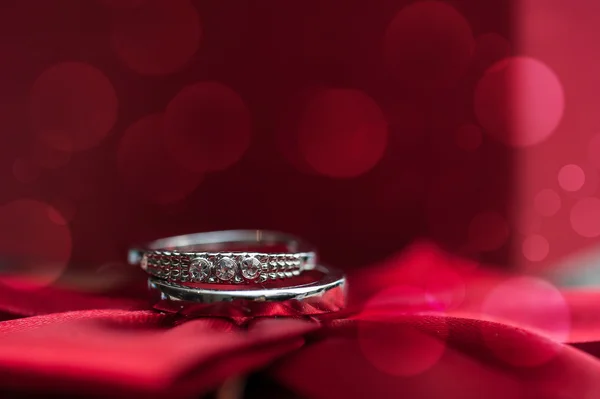 Dos anillos de boda sobre fondo rojo con bokeh — Foto de Stock