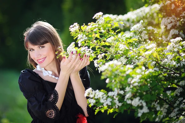 Mulher feliz em um jardim de primavera segurando flores — Fotografia de Stock