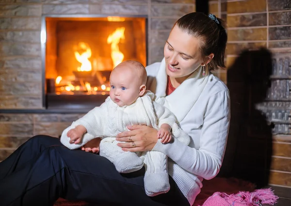 Anne ile bebek kız şömine tarafından — Stok fotoğraf