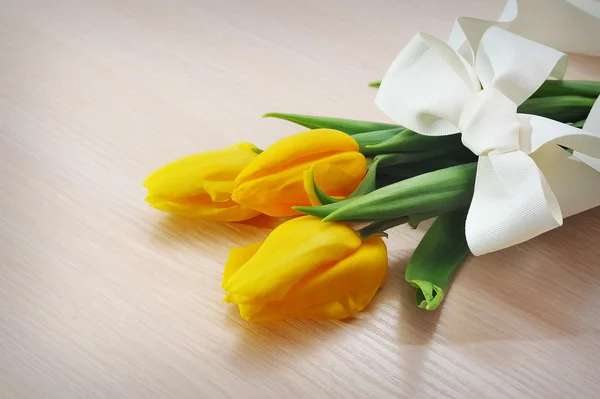 Drie gele tulpen op een houten achtergrond — Stockfoto