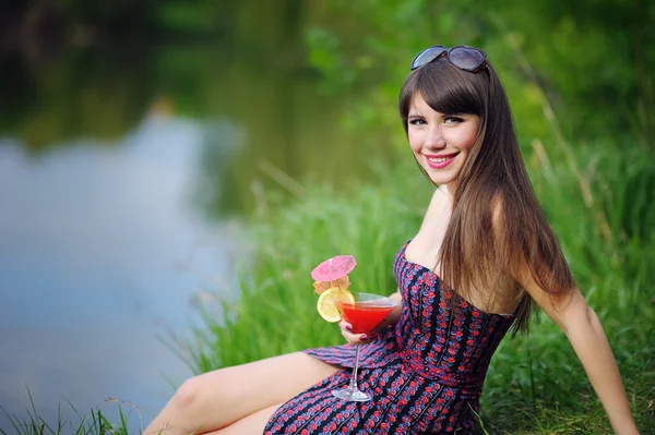 Schönes Mädchen mit Blumen in den Händen auf grünem Gras sitzend — Stockfoto