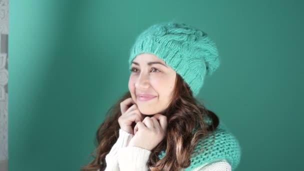 Chica sonriente en un sombrero de punto turquesa posando en la cámara — Vídeos de Stock