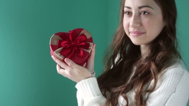 Hermosa chica sosteniendo un regalo en forma de corazón — Vídeos de Stock