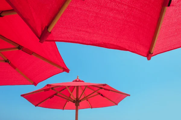 Kırmızı plaj şemsiyesi güneşli mavi gökyüzü karşı — Stok fotoğraf