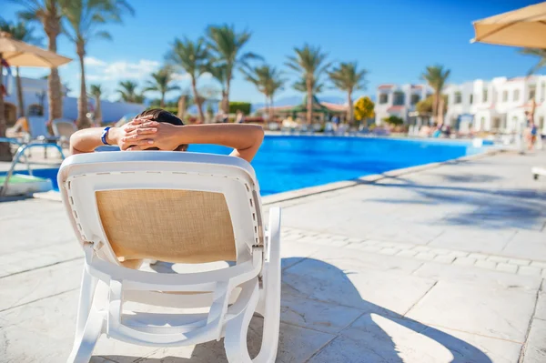Femme allongée sur une chaise longue au bord de la piscine de l'hôtel — Photo