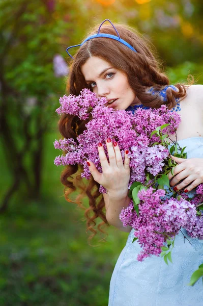 Beautiful young woman standing in the garden with a branch of li — Stock Photo, Image