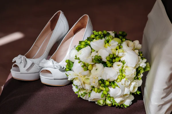 White bridal bouquet and white shoes on the brown chair — Stock Photo, Image
