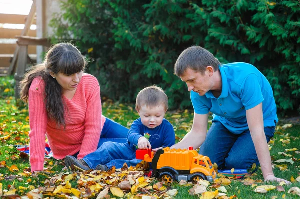 Familia joven con un niño pasea en el parque de otoño —  Fotos de Stock