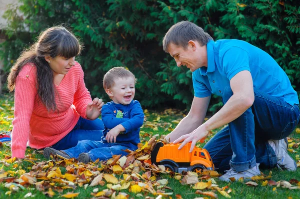 Familia joven con un niño pasea en el parque de otoño —  Fotos de Stock