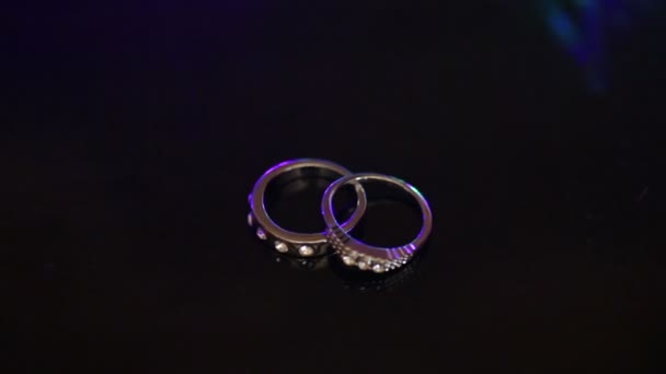 Two rings are on the table at the flashing multicolored background — Stock Video