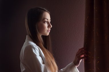 güzel bir kız pencereden dışarı bakarak