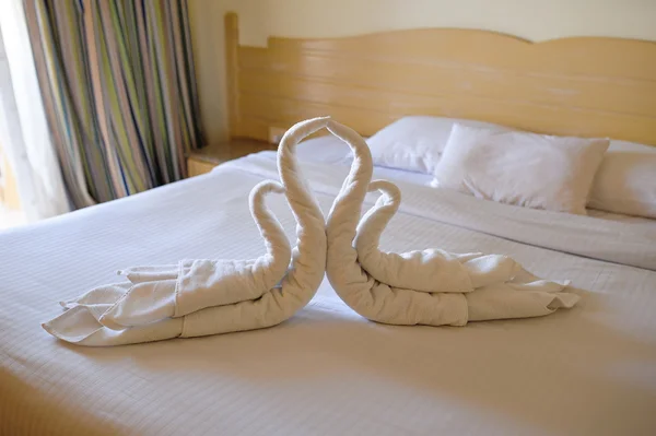 Tucked bed with swans out of towels in a hotel room — Stock Photo, Image