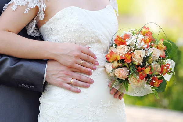 Marié embrasse la mariée, la mariée tient un bouquet de mariage — Photo