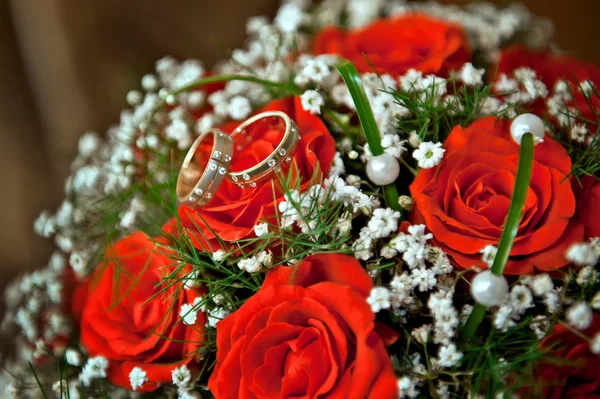 Bagues mariée et marié au bouquet de mariage de roses rouges — Photo