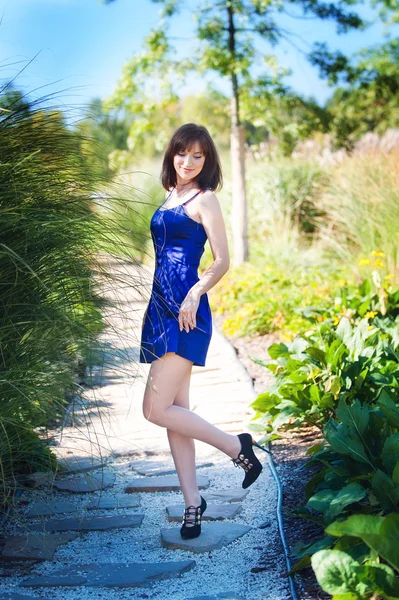 Beautiful woman in a blue dress walks in the park — Stock Photo, Image