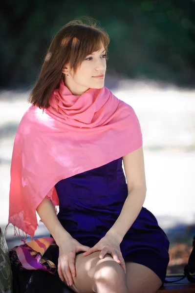 Mulher bonita em um vestido azul sentado em um banco no parque — Fotografia de Stock