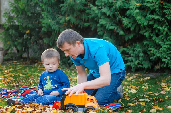 Vader en zoon spelen in de park speelgoedauto in een park op het gras — Stockfoto