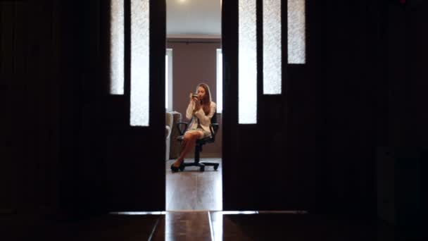 Mujer sentada en una silla en la habitación y maquillada — Vídeos de Stock