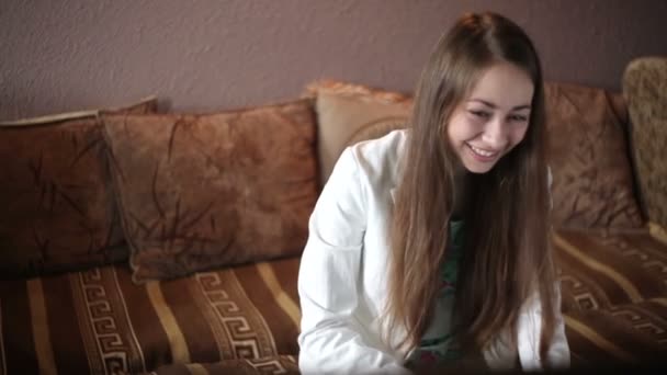 Belle femme assise sur le canapé et regardant la télévision — Video