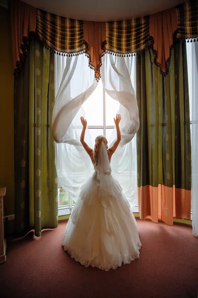 Невеста в белом платье в гостиничном номере у окна — стоковое фото