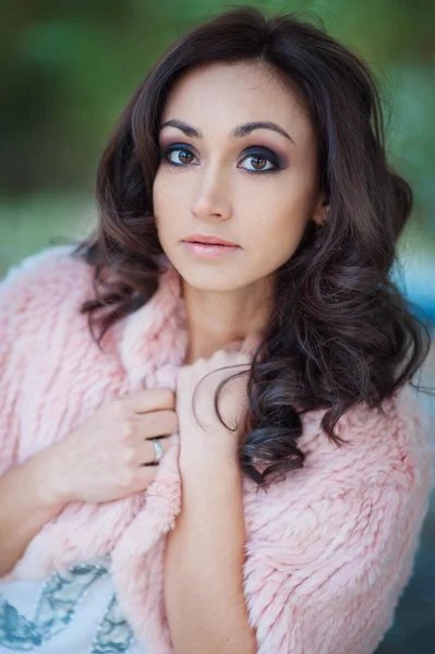 Beautiful woman in a pink cape walks in the park — Stock Photo, Image