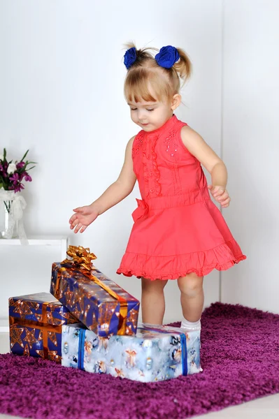 Niña en vestido rojo mirando regalos —  Fotos de Stock