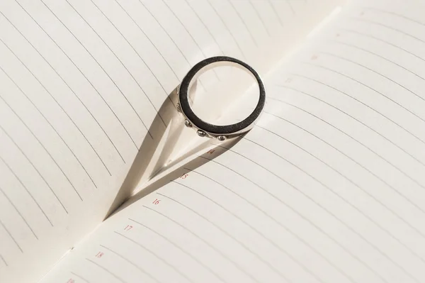 Обручальное кольцо находится на странице дневника и делает тень в виде — стоковое фото