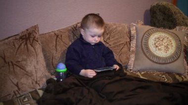 Kanepede oturan ve smartphone bir karikatür izlerken küçük çocuk