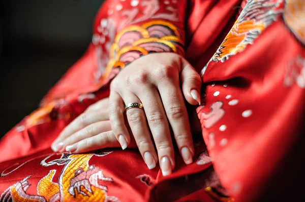 Handen van een bruid in een rood gewaad met een wedding ring aan haar vinger — Stockfoto