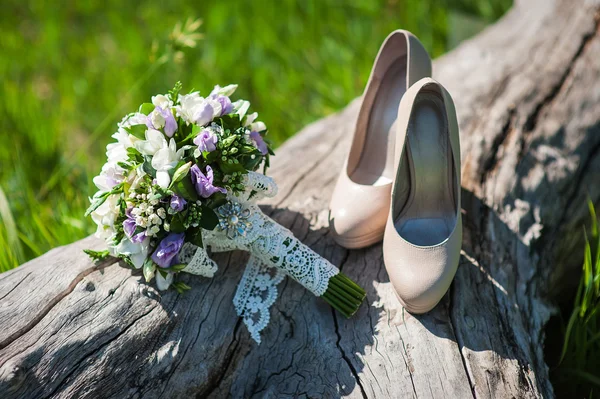 Hermoso ramo de boda y zapatos para la novia de pie en un — Foto de Stock