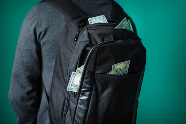 Mann mit schwarzem Rucksack, aus dem Dollars ragen — Stockfoto