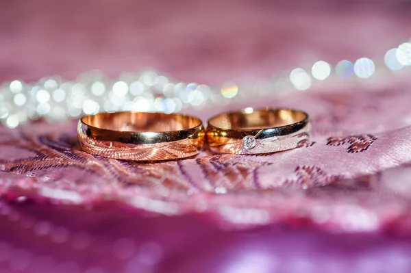 Dos anillos de boda de oro yacen sobre una almohada —  Fotos de Stock