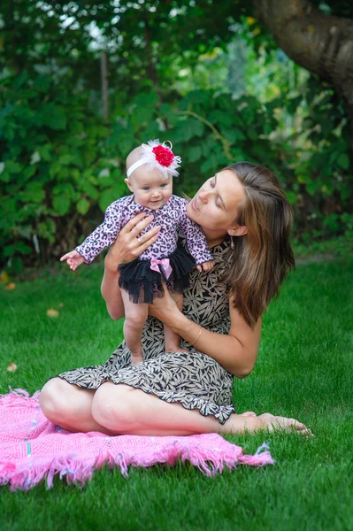 Mãe feliz e pequena menina descansando no jardim de verão — Fotografia de Stock