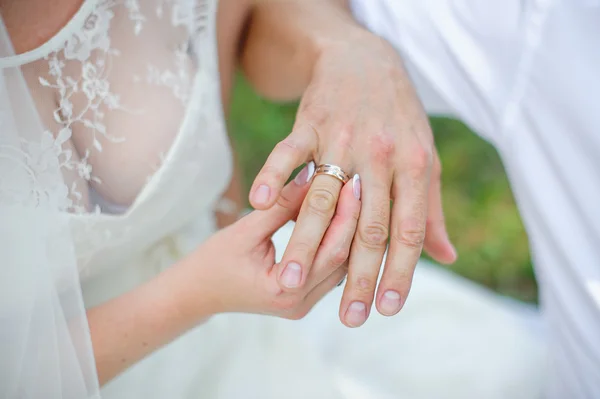 Noiva usa uma aliança de casamento de ouro no dedo do noivo — Fotografia de Stock