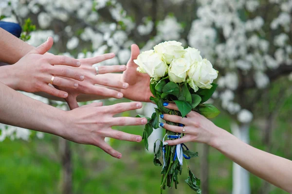 Bride holds a wedding bouquet and hands reaching for him — Stock Photo, Image