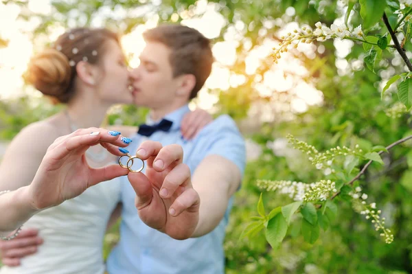 Bride and groom holding rings and kiss — Stock Photo, Image