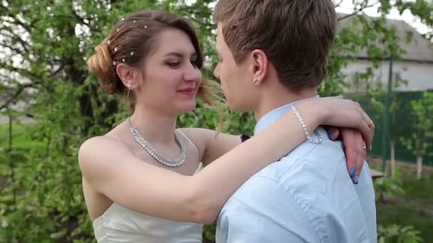 Bride groom gently embraces the neck in the spring garden — Stock Video