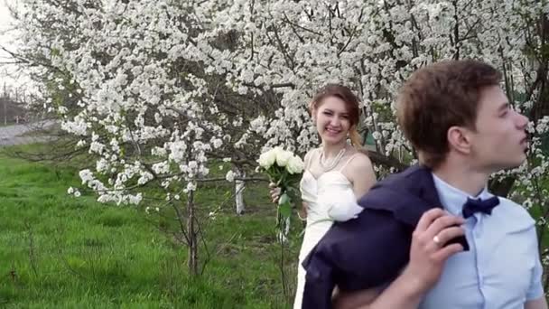 Novia y novio están en el floreciente jardín de primavera — Vídeo de stock