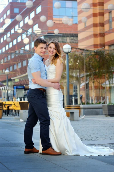 Happy bride and groom walking on a street of city — Stock Photo, Image