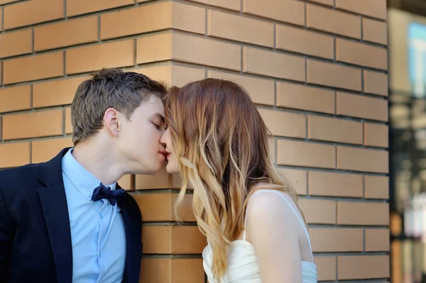 Bride and groom stand on the corner of a brick building look at each one — Stock Photo, Image