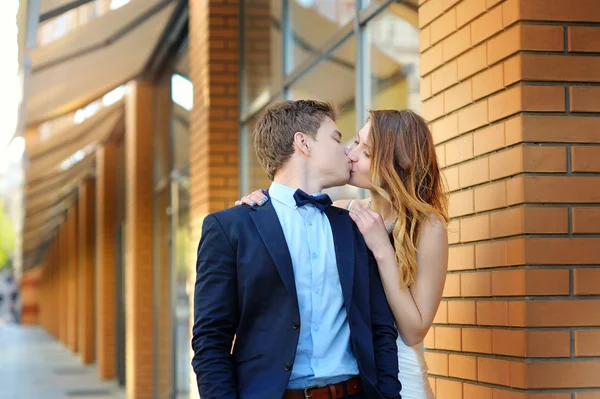 Bride and groom stand on the corner of a brick building look at each one — Stock Photo, Image