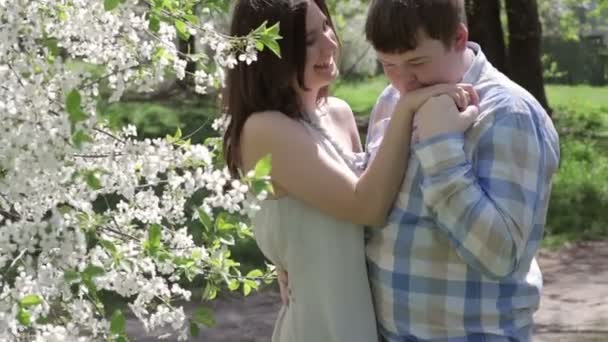 Uomo innamorato in piedi vicino a un albero fiorito e baciare la mano di una donna in primavera — Video Stock