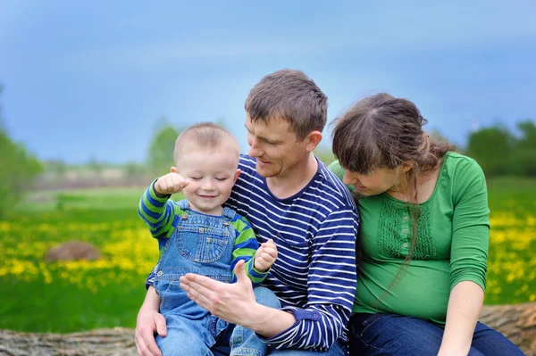 Young family walking on the meadow with yellow flowers in spring — Stock Photo, Image