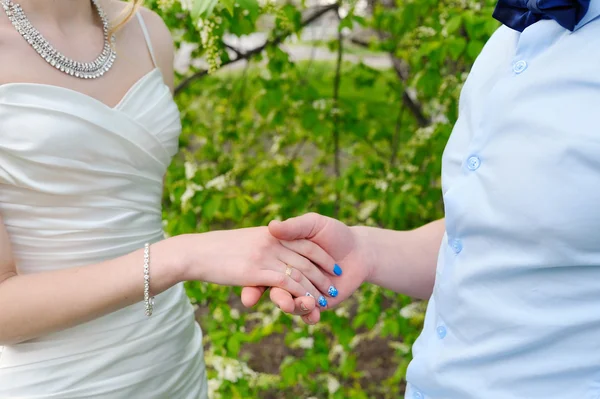 Marié tient la main de sa mariée dans la nature close-up — Photo