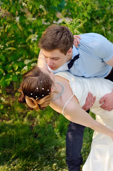 Bruden och brudgummen på bröllop dag promenader utomhus på våren i grön park — Stockfoto