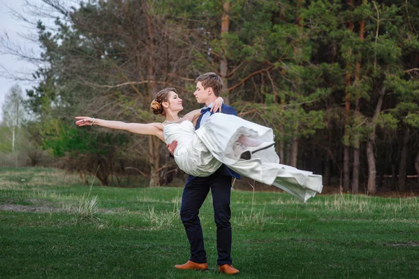 Groom holds bride in his arms and smiles of happiness — Stock Photo, Image