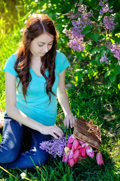 美しい女性がバスケットに花を置く — ストック写真