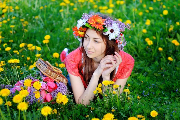 Mulher bonita em um vestido vermelho deitado no prado com flores amarelas — Fotografia de Stock